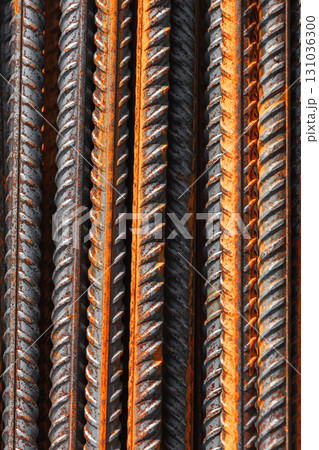Detailed vertical macro photo of steel reinforcement bars featuring orange rust 131036300