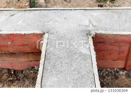 A concrete foundation is being formed between red wooden boards A concrete foundation is being formed between red wooden boards 131036304