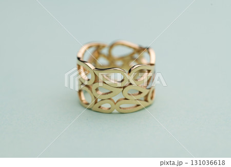 A gold ring with a design of leaves and a hole in the middle 131036618