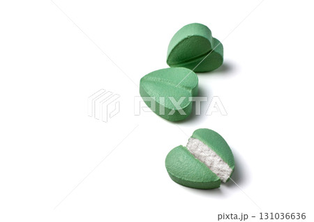 turquoise colored heart shaped cardiology pills cut in half close-up isolated on white background 131036636