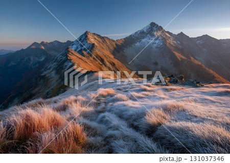 Breathtaking sunrise over frosty mountain peaks with golden light. 131037346