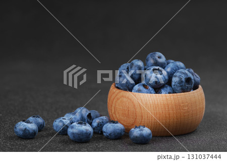 Fresh ripe blueberries in wooden bowl on dark gray stone background closeup macro healthy food Fresh ripe blueberries in wooden bowl on dark gray stone background closeup macro healthy food 131037444