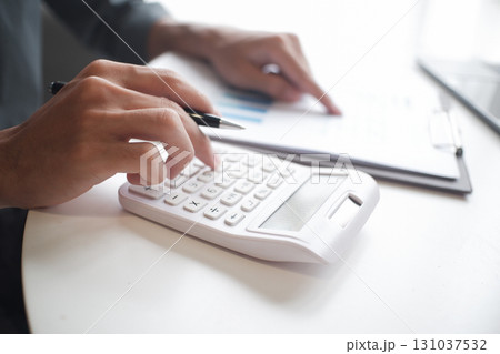 Closeup hand of businessman using calculator, laptop and reading report in office Closeup hand of businessman using calculator, laptop and reading report in office 131037532