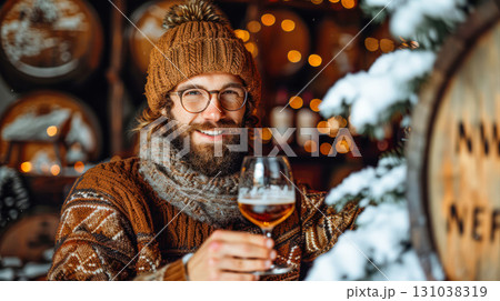 Bearded man in cozy sweater holding a glass of beer in a festive winter setting with lights 131038319