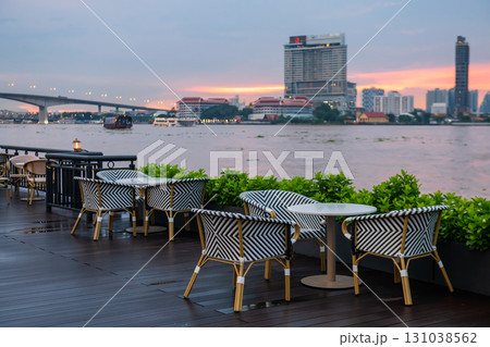 seats of outdoor cafe riverbank by Chao Phraya river at dusk, Bangkok 131038562