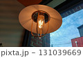 Warm glowing vintage edison bulb pendant light in cozy cafe interior 131039669
