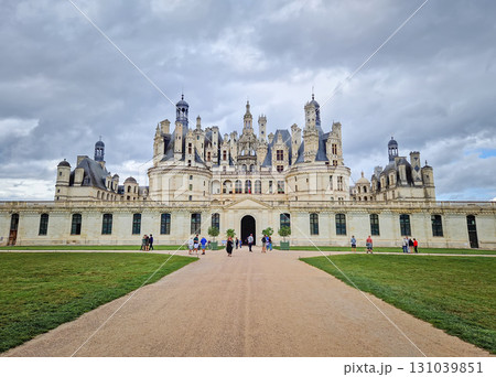 Chambord, Loir-et-Cher, France  - August 30, 2023 Chateau de Chambord, a majestic medieval castle with green gardens. Iconic French Renaissance architecture palace, under a dramatic, cloudy sky 131039851