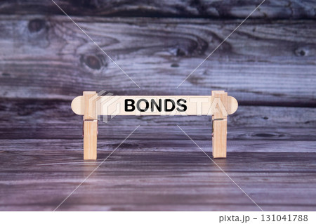 Bonds symbol. A wooden stick secured by Clothespins set over beautiful Realistic Wooden Texture Background. Business and Bonds concept with copy space Bonds symbol. A wooden stick secured by Clothespins set over beautiful Realistic Wooden Texture Background. Business and Bonds concept with copy space 131041788