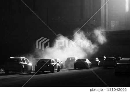 City street traffic with cars emitting steam and light creating moody winter atmosphere 131042003