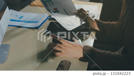 Close-up of businessman's hands making notes, mobiles, chart, desk, office 131042223