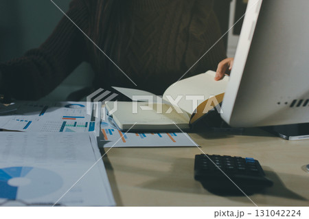 Close-up of businessman's hands making notes, mobiles, chart, desk, office 131042224