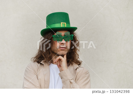 Man Wearing Shamrock clover glasses and Green St. Patrick's Hat against beige wall. Space for design. 131042398