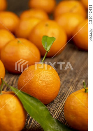 Unpeeled tangerines stacked together, a large number of ripe orange tangerines on the table Unpeeled tangerines stacked together, a large number of ripe orange tangerines on the table 131042451