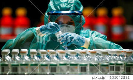 Medical professional in protective gear preparing vaccine vials in a laboratory setting with colorful background 131042851
