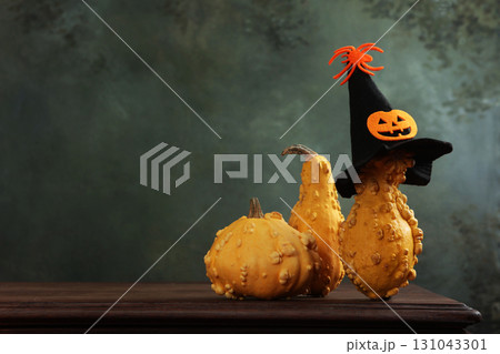 Pumpkins on table. Funny spider hat is on pumpkin. There are several pumpkins on table. Halloween holiday. Copy space. 131043301