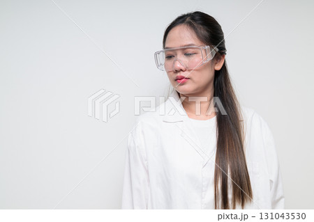 Asian healthcare worker scientist woman in lab coat wearing safety goggle glasses thinking Asian healthcare worker scientist woman in lab coat wearing safety goggle glasses thinking 131043530