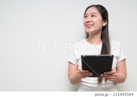Portrait of young Asian woman using digital tablet computer against white background Portrait of young Asian woman using digital tablet computer against white background 131043564