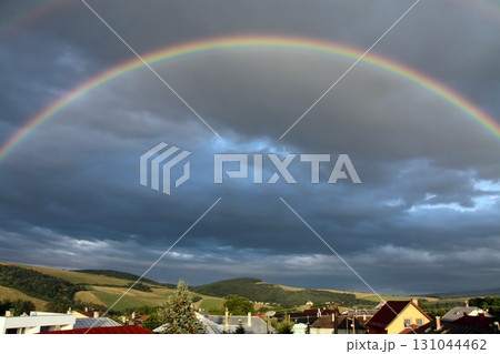 Vibrant rainbow arching across a dramatic cloudy sky Vibrant rainbow arching across a dramatic cloudy sky 131044462