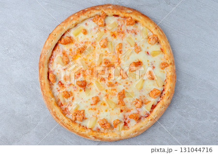 Hawaiian Style Pizza with Chicken, Pineapple, and Melted Cheese on Crispy Crust over Gray Stone Background Hawaiian Style Pizza with Chicken, Pineapple, and Melted Cheese on Crispy Crust over Gray Stone Background 131044716