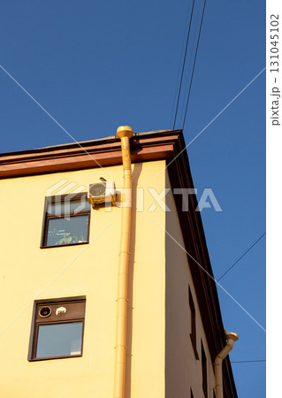 Air conditioners on the facade of a yellow house against a blue sky. An air ventilation. 131045102