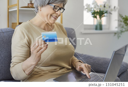 Portrait of happy smiling mature senior woman using credit card making online payment at home Portrait of happy smiling mature senior woman using credit card making online payment at home 131045251