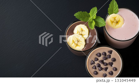 Top-down view of three vibrant smoothies adorned with banana slices 131045449