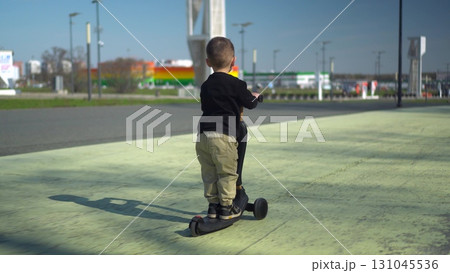 A Happy Child Riding a Bright Scooter in the Open Park, Enjoying an Adventurous Day A Happy Child Riding a Bright Scooter in the Open Park, Enjoying an Adventurous Day 131045536