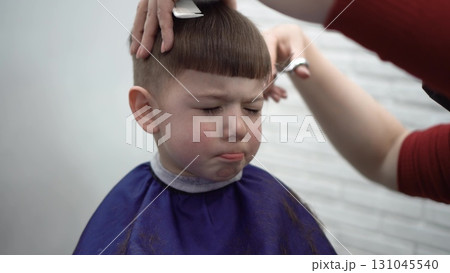 child squinting during haircut at barber child squinting during haircut at barber 131045540