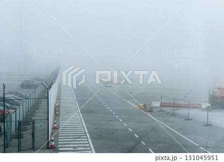 A dense fog blankets an airport tarmac, creating a surreal and hazy atmosphere. 131045951
