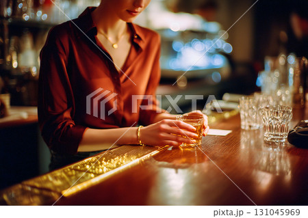A woman is sitting at a bar with a glass of liquor in her hand 131045969
