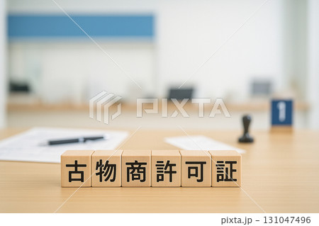 行政窓口カウンターを背景にした古物商許可証ウッドブロック｜公的手続きイメージ 131047496