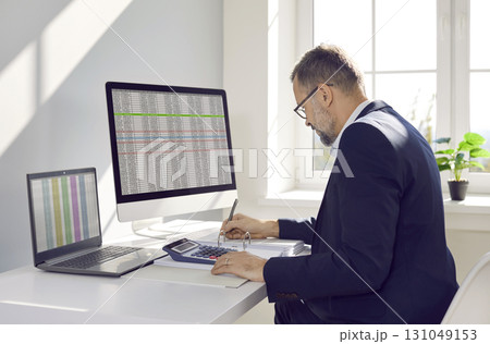 Mature business accountant or auditor working with spreadsheets on office computers Mature business accountant or auditor working with spreadsheets on office computers 131049153