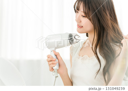 ヘアドライヤーでヘアブロー・髪の毛を乾かす女性（ヘアケア） 131049239