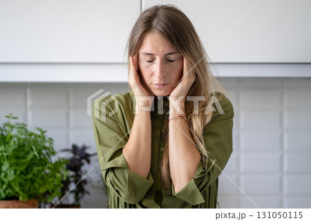 Exhausted woman holding temples at home, headache nausea and physical collapse from overexertion Exhausted woman holding temples at home, headache nausea and physical collapse from overexertion 131050115