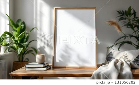 Blank white frame on a wooden table surrounded by books and plants, ideal for a poster mockup display 131050202