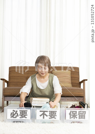 リビングで断捨離をするシニア女性 リビングで断捨離をするシニア女性 131052724
