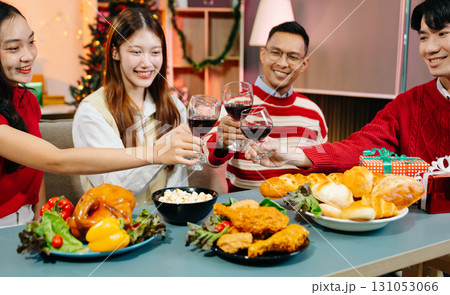 Asian friends capture the holiday spirit with gifts, laughter, and a festive Christmas dinner in a cozy, joy-filled setting Asian friends capture the holiday spirit with gifts, laughter, and a festive Christmas dinner in a cozy, joy-filled setting 131053066