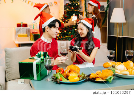 Asian friends capture the holiday spirit with gifts, laughter, and a festive Christmas dinner in a cozy, joy-filled setting Asian friends capture the holiday spirit with gifts, laughter, and a festive Christmas dinner in a cozy, joy-filled setting 131053297