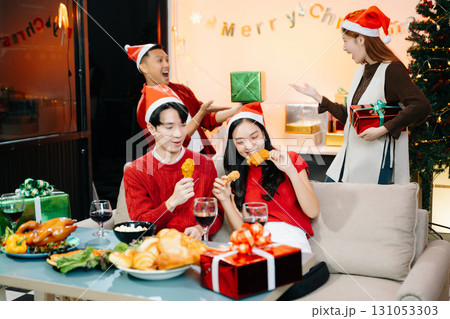 Holiday spirit with Asian friends exchanging gifts, sharing laughs, and enjoying a festive Christmas 131053303