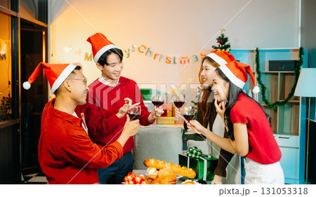 Holiday spirit with Asian friends exchanging gifts, sharing laughs, and enjoying a festive Christmas dinner Holiday spirit with Asian friends exchanging gifts, sharing laughs, and enjoying a festive Christmas dinner 131053318