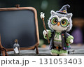 A cute little crocheted owl doll dressed in a witch's costume poses as if teaching a class. 131053403