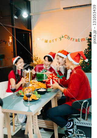 Holiday spirit with Asian friends exchanging gifts, sharing laughs, and enjoying a festive Christmas dinner 131053439