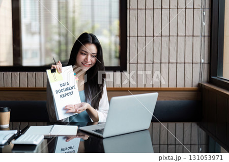 Smiling businesswoman presenting a data report on a laptop, showcasing professionalism and organization. Smiling businesswoman presenting a data report on a laptop, showcasing professionalism and organization. 131053971