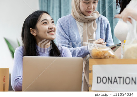 Diverse women collaborating on donation project, discussing contributions and community support in a modern workspace. Diverse women collaborating on donation project, discussing contributions and community support in a modern workspace. 131054034