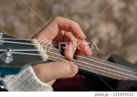Close up of female hands playing guitar ukulele and singing relaxing enjoying outdoors on sunny autumn day. Hippie woman in boho style training playing musical instrument. Fall leaves Close up of female hands playing guitar ukulele and singing relaxing enjoying outdoors on sunny autumn day. Hippie woman in boho style training playing musical instrument. Fall leaves 131054132