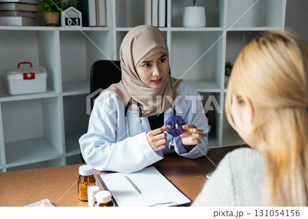 Compassionate doctor explaining medication to a patient in a welcoming healthcare environment. 131054156