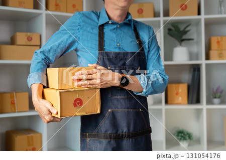 Entrepreneur carrying stacked packages for online business, showcasing the hands-on nature of startup logistics. 131054176