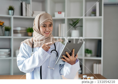 Friendly doctor using a tablet to explain treatment options to a patient in a modern healthcare environment. 131054210