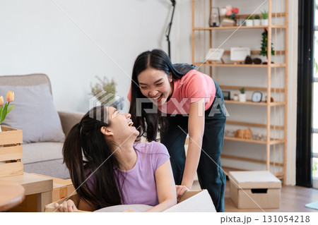 Diverse female couple laughing together while unpacking boxes in their new home. Diverse female couple laughing together while unpacking boxes in their new home. 131054218