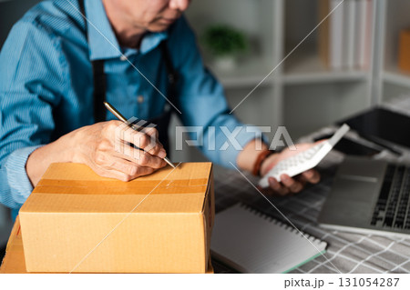 Entrepreneur managing online sales, packing orders in a startup office environment. 131054287